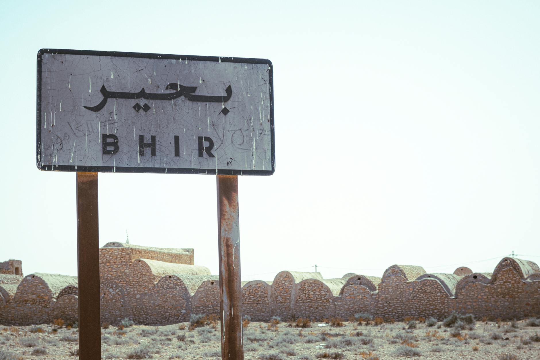 Znak Bhir na pustynnym tle Tataouine z tradycyjną tunezyjską zabudową