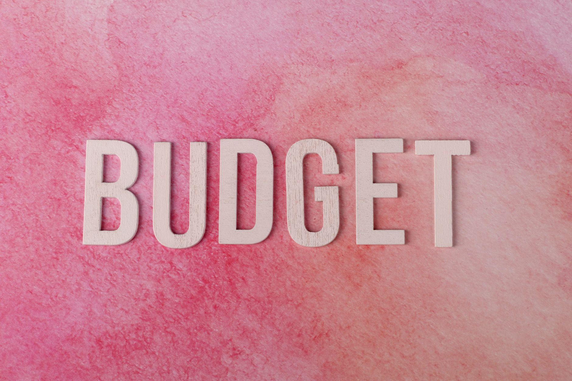 Napis BUDGET na różowym tle jako symbol planowania kosztów podróży Napis BUDGET na różowym tle jako symbol planowania kosztów podróży