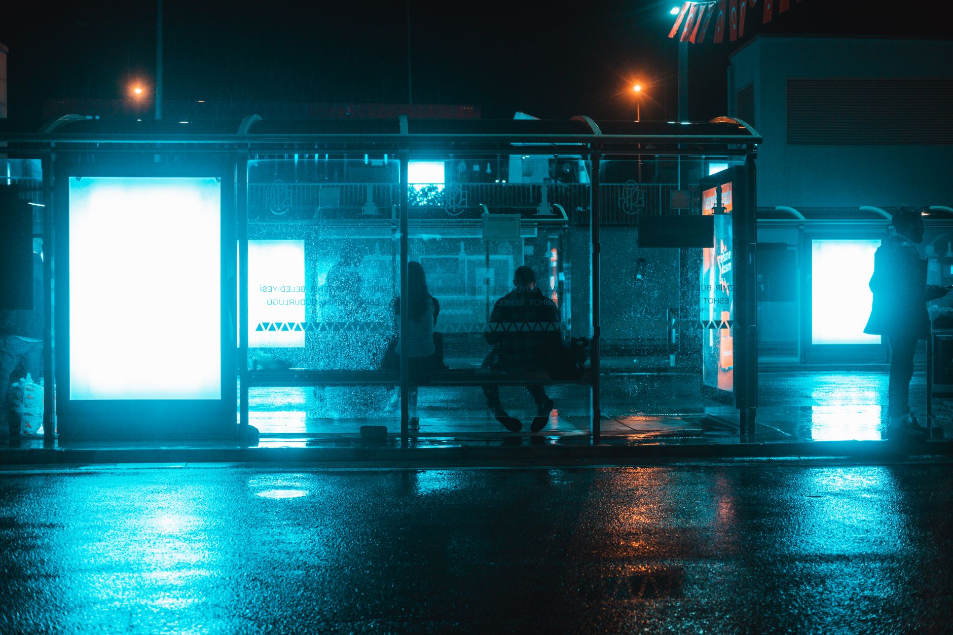 Nocny przystanek autobusowy w polskim mieście, mokry chodnik i neon