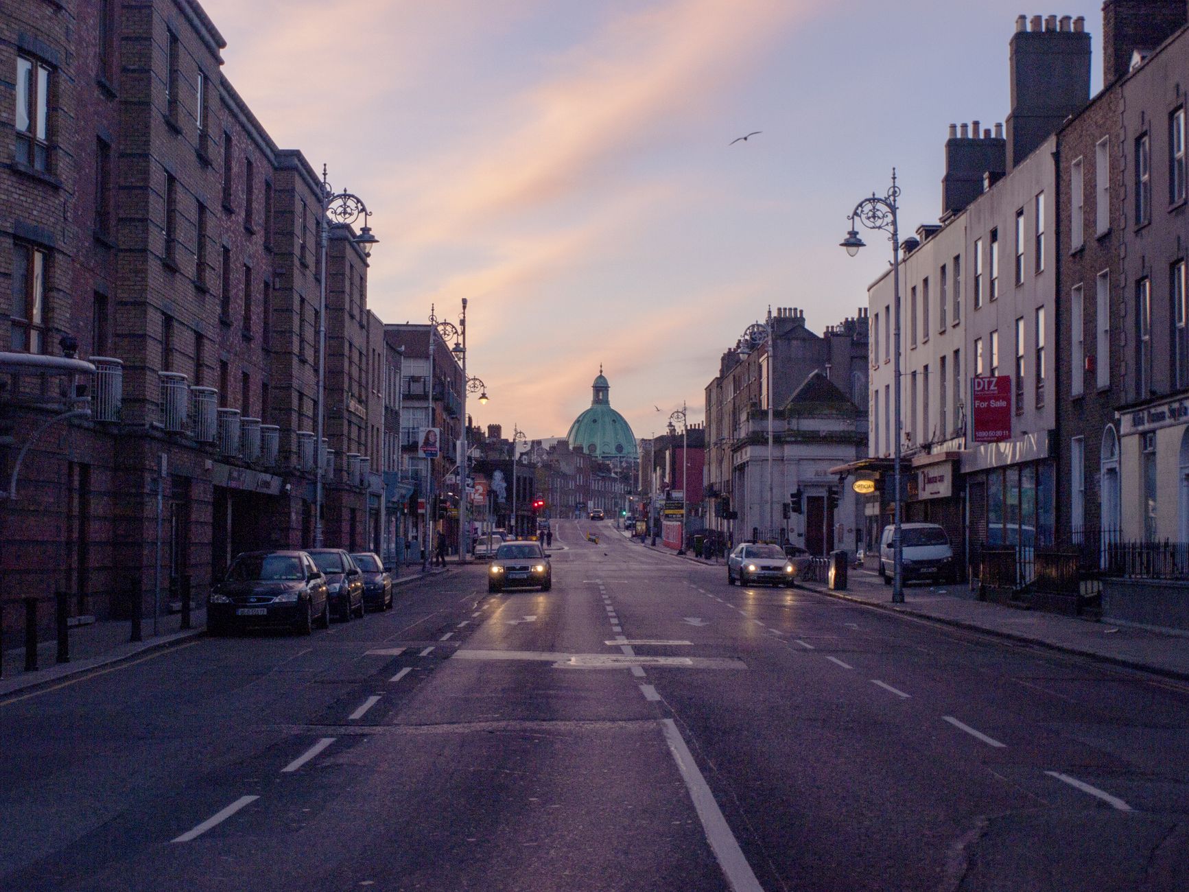 Spokojna ulica w Dublinie o wschodzie słońca, auta i kopuła budynku